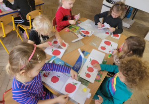 Dzieci wykonują zadanie tygodniowe - wycinają i układają jabłka według wielkości