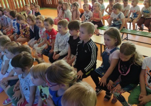 Dzieci z zaciekawieniem oglądają występ magika.