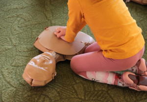 Dziecko ćwiczy udzielanie pierwszej pomocy na fantomie.