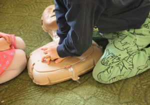 Dziecko ćwiczy udzielanie pierwszej pomocy na fantomie.