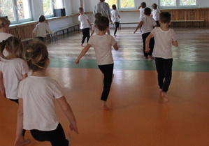 Dzieci ćwiczą na sali gimnastycznej.