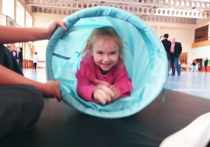 Dziewczynka pokonująca gimnastyczny tunel.