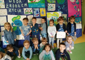 Dzieci ubrane na niebiesko stoją przed wystawą nt. "Woda źródłem życia"