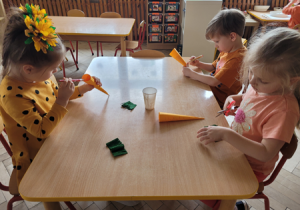 Dzieci wykonują papierowe marchewki.
