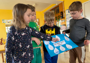 Dzieci w zespole prezentują wykonany przez siebie plakat "Do czego służy woda".