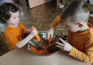Dzieci przygotowują surówkę z marchewki.