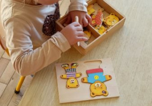 Dziecko układa drewnianego misia.