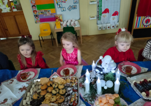 Dzieci siedzą przy stole podczas świątecznego poczęstunku.