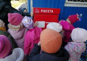 Dzieci wysyłają list podczas wizyty na poczcie.
