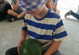Chłopiec odgaduje jaki to owoc wykorzystując dotyk.