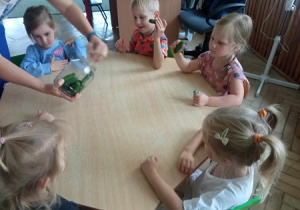 Dzieci wkładają ogórki do słoika.