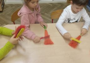 Dzieci tworzą marchewki z sizalu podczas warsztatów.
