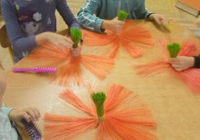 Dzieci tworzą marchewki z sizalu podczas warsztatów.