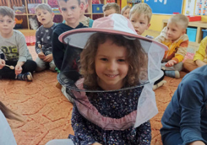 Dziewczynka w kapeluszu pszczelarskim.