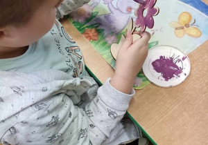Chłopiec maluje kwiatka dla dziadka.