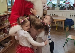 Dzieci przytulają Mikołaja.