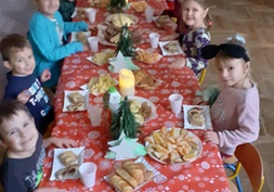 Dzieci siedzą przy stole podczas poczęstunku z okazji Świąt Bożego Narodzenia