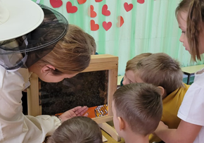 Dzieci biorą udział w warsztatach pszczelarskich.