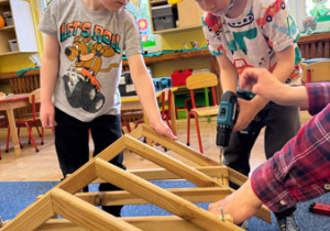 Dzieci podczas warsztatów budują konstrukcję domku.