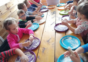Dzieci ugniatają i formują ciasto na chlebek.