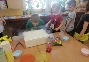 Dzieci dmuchają do pudełka z suchym lodem, dzięki czemu powstawała mgła.