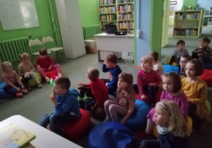 Wizyta w Bibliotece Miejskiej. Dzieci słuchają opowiadań o historii najstarszych zabawek.