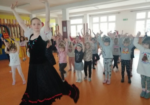 Dzieci wraz z tancerką, uczą się podstawowych kroków jednego z tańców ludowych